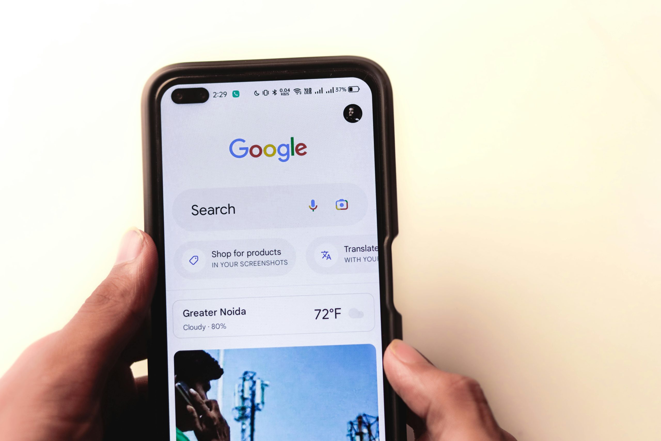 A close-up of a hand holding a smartphone with Google search displayed on the screen.